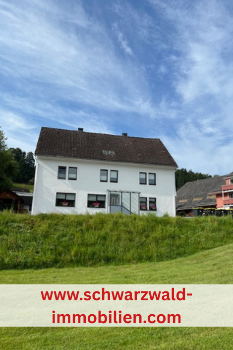Haus vor einer Hecke und Wiese