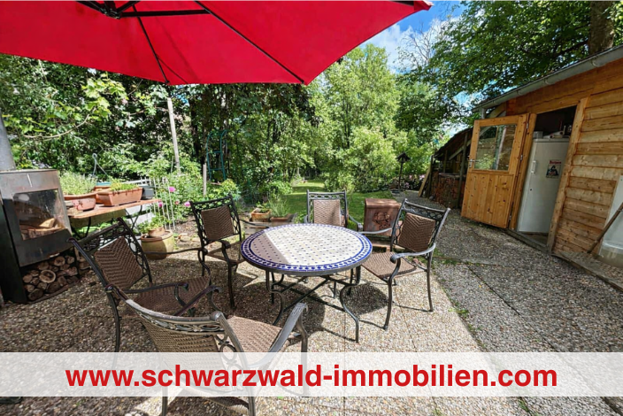 Garten mit rotem schirm und sitzgruppe am tisch